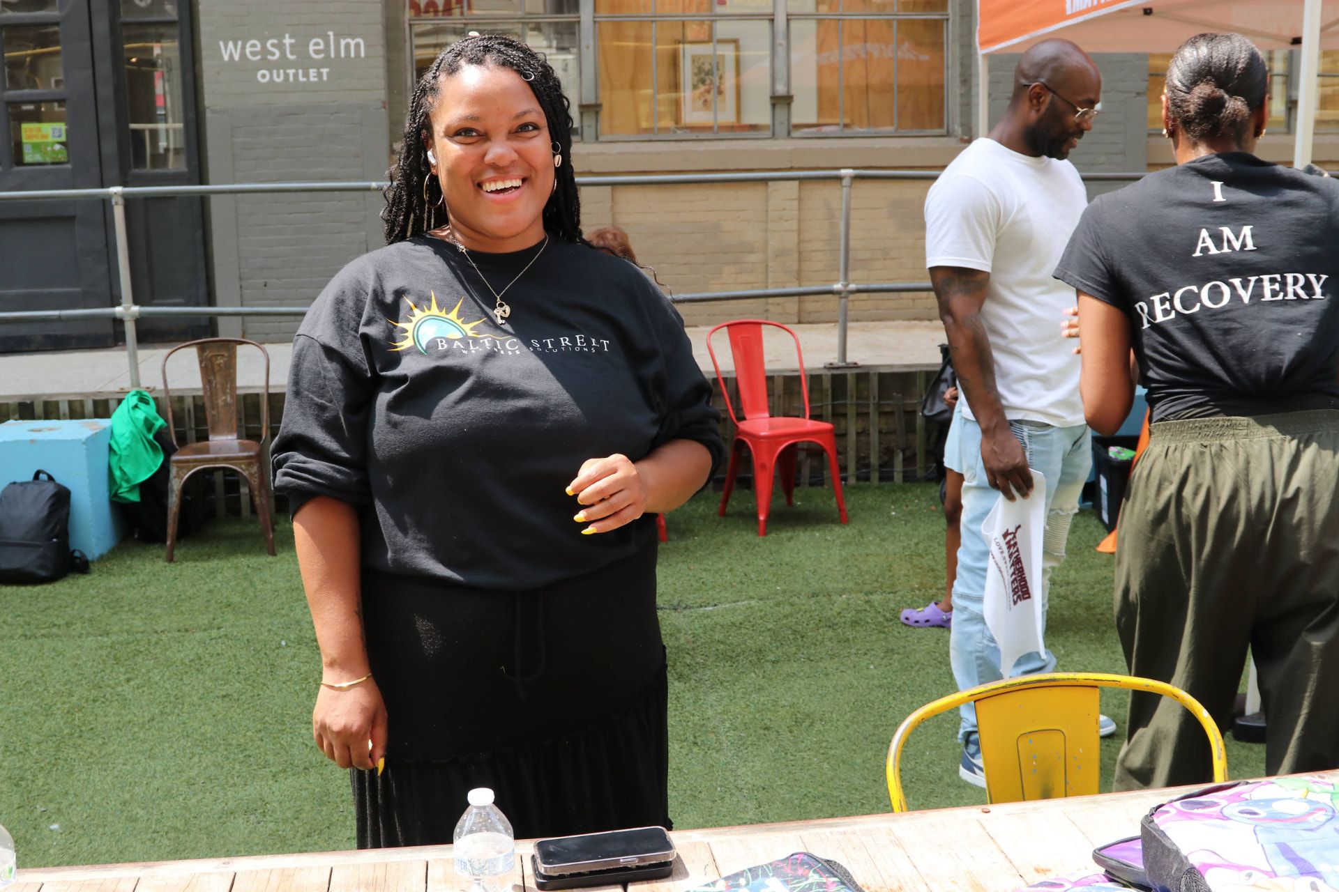 A smiling Baltic Street team member at an outreach table